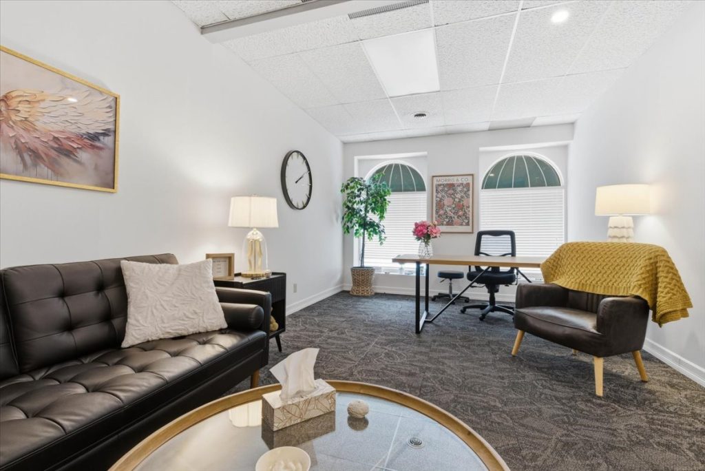 Therapy office with a leather sofa, work desk and arched windows