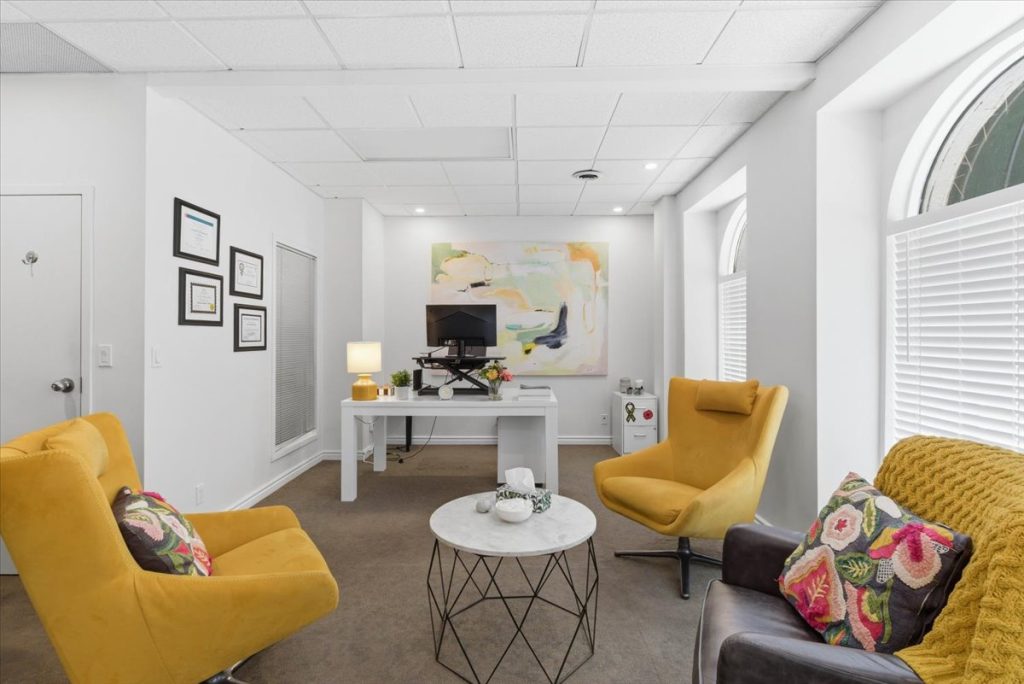 Therapy office with two yellow armchairs, a sofa and a white desk