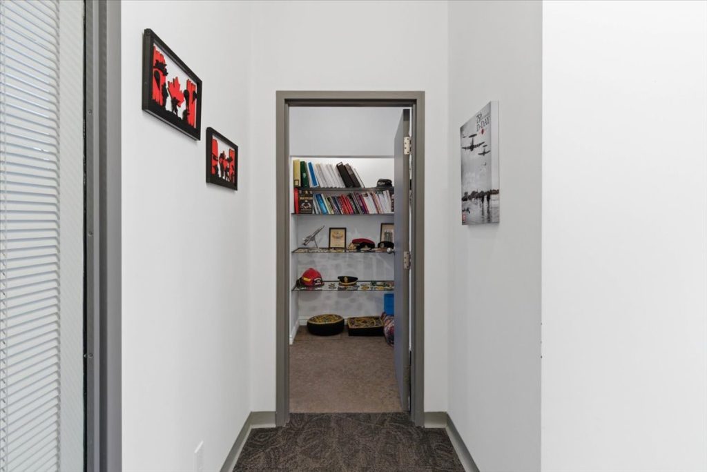 Hallway leading to an office with bookshelves and Canadian-themed artwork