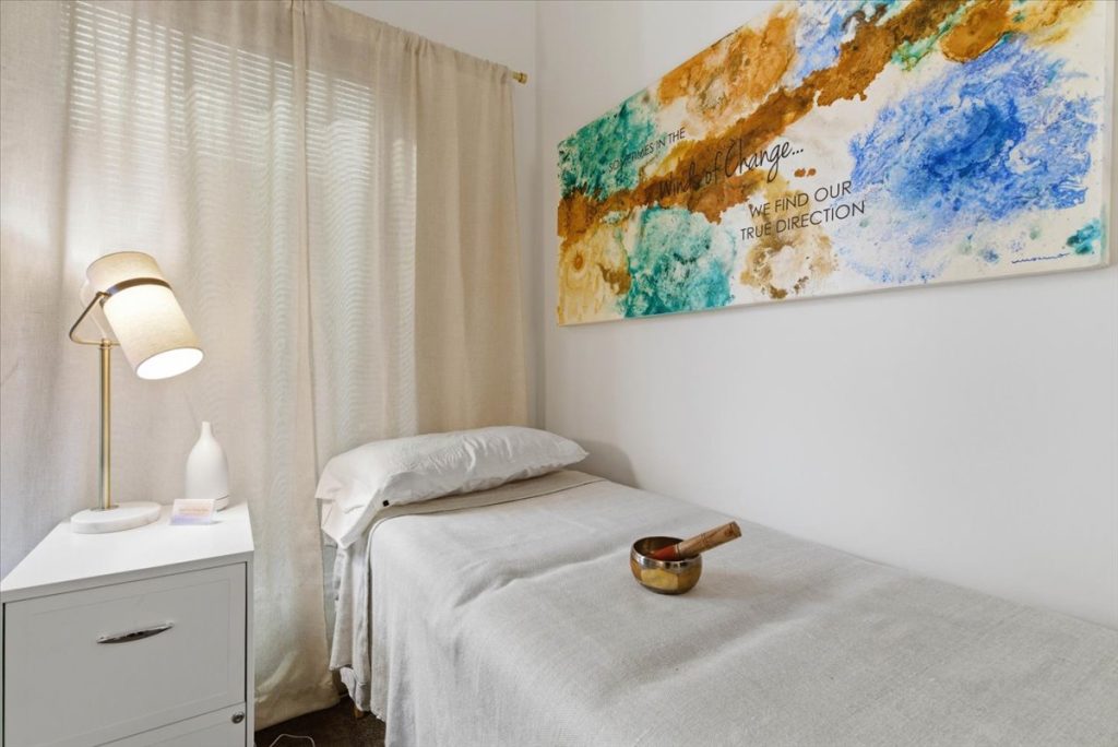 Treatment room with a therapy table, singing bowl and inspirational wall art