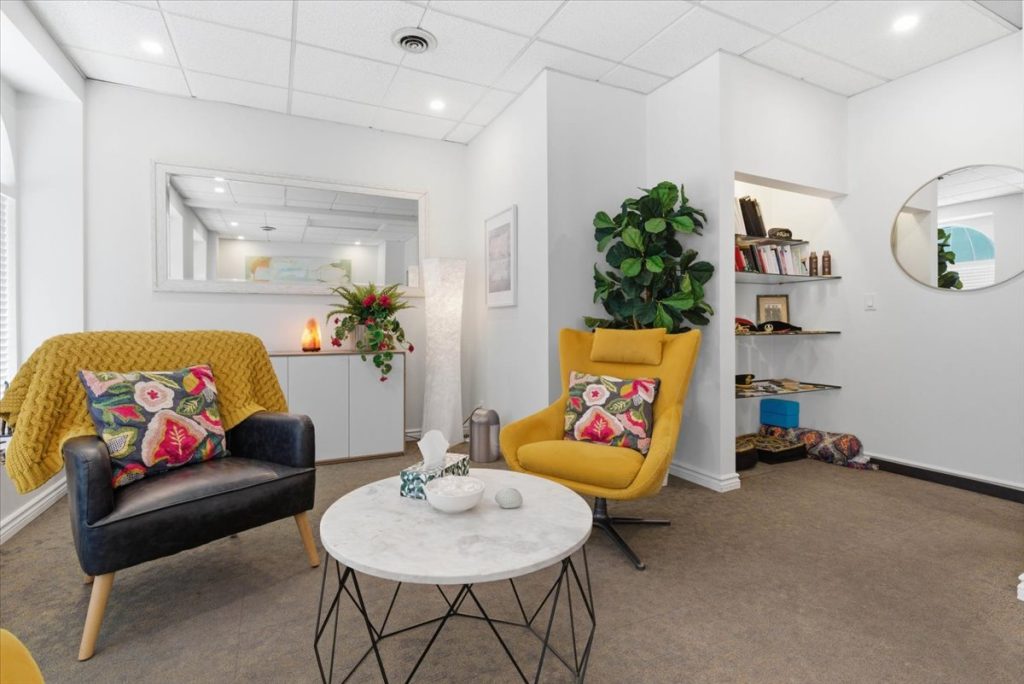 Therapy office with a yellow armchair, sofa and marble coffee table