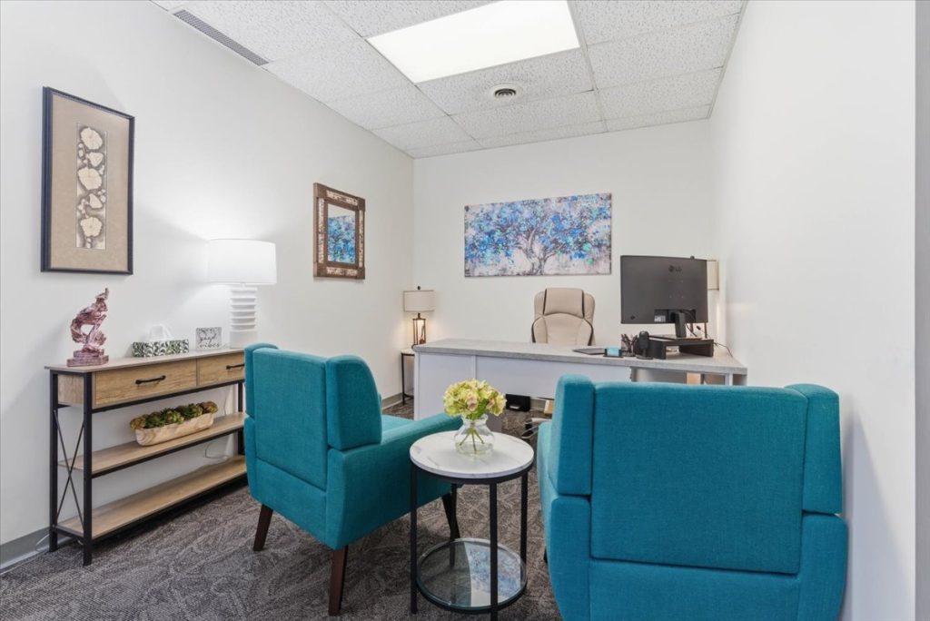 Nurse practitioner office with two teal armchairs and a desk