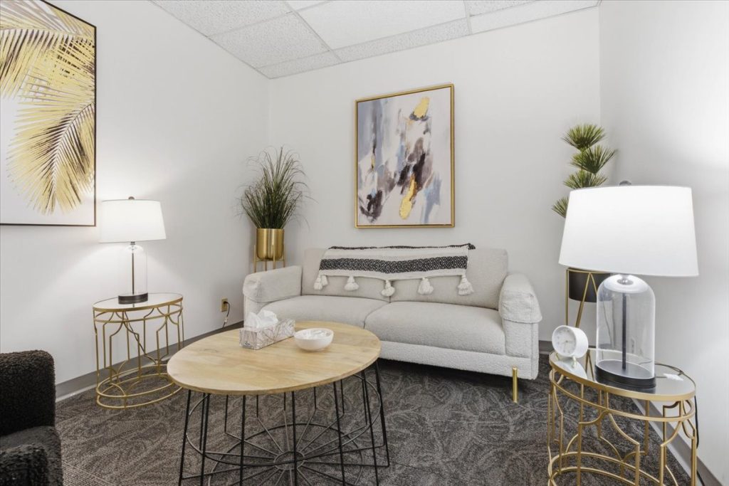 Therapy room with a light grey sofa, coffee table and gold-accented decor
