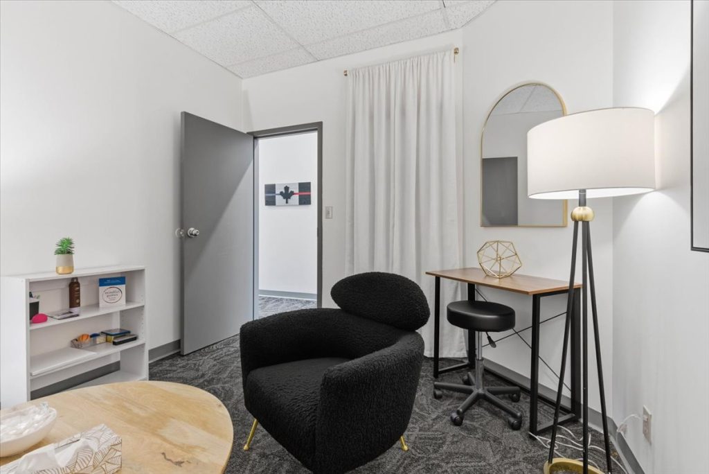 Therapy room with a black armchair, small desk and floor lamp